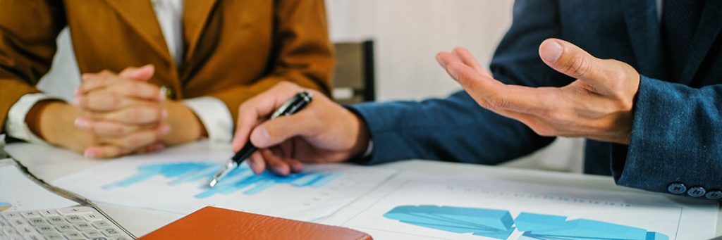 Dois homens de terno analisando gráficos em documentos