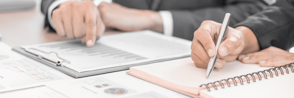 Duas mãos aparecem na imagem uma apontando para um folha e a outra escrevnedo em nova folha.